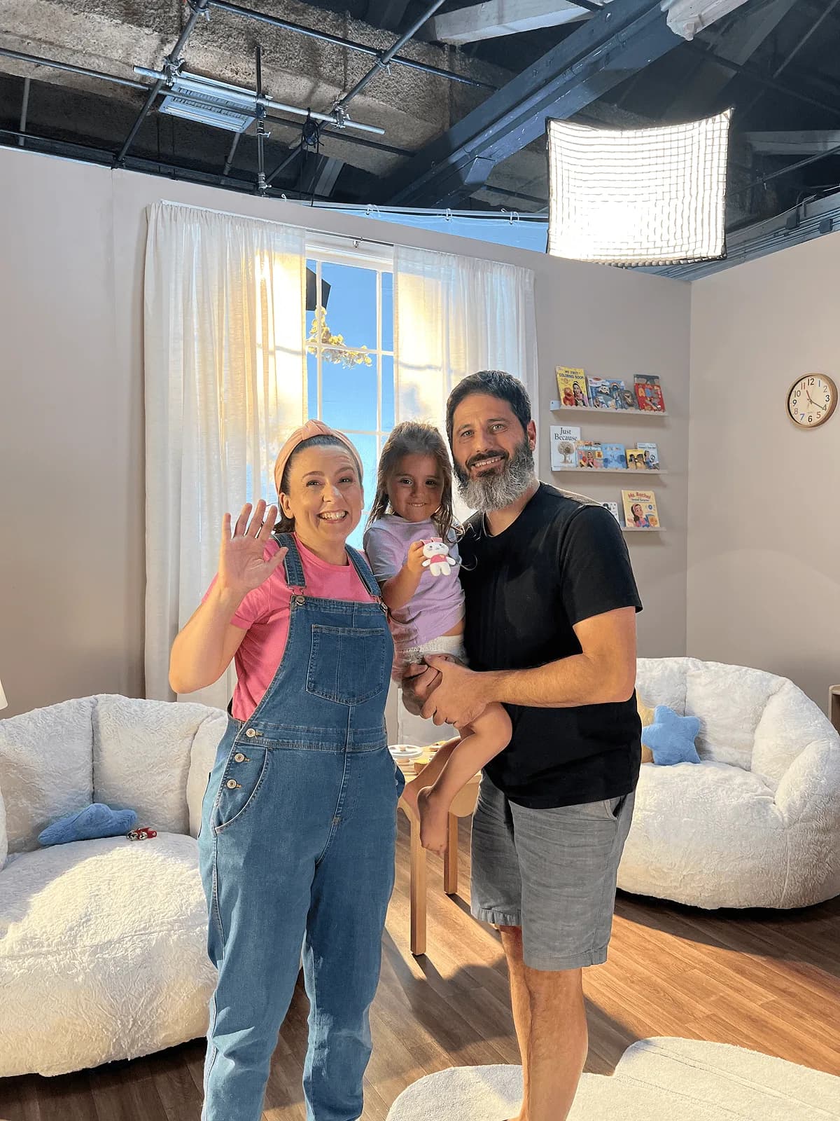 Ms. Rachel waving beside a crew member holding a child on the Millie Moon playroom set