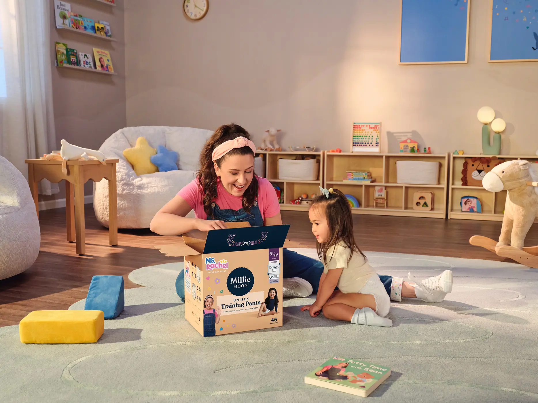 Ms. Rachel and a toddler opening a box of Millie Moon Ms. Rachel edition Luxury Training Pants in a playroom